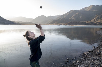 Woman putting mud on hands and face while enjoying outdoors in nature.