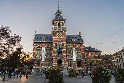 Twon hall of anderlecht at sunset. families and people enjoying the sunset at town hall square