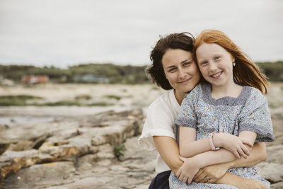 Mother and daughter embracing at seaside