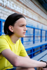 Portrait of a pensive teen boy. teenager sitting on stadium stairs.  melancholic guy  lonely. 