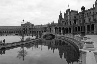 Reflection of plaza de espana on canal against sky