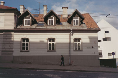 Man walking on road against buildings