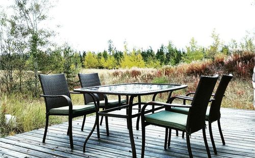 Chairs and table by trees against sky