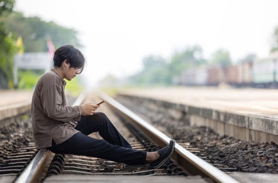 Depressed young man sitting on railway track person