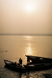 Silhouette people on boat against sky during sunset