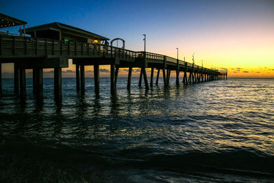 Pier over sea against sky during sunset