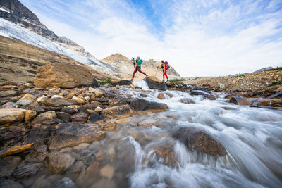 People on rock in water against sky