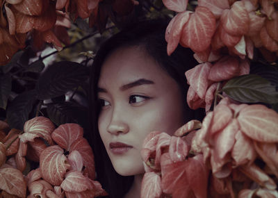 Close-up portrait of young woman with red leaves