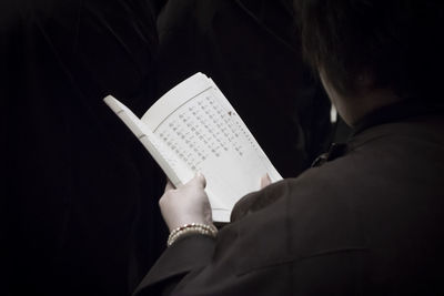 Rear view of man reading book on paper