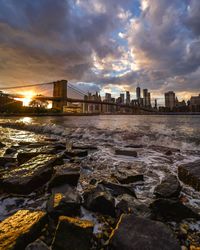 Sea by buildings against sky during sunset