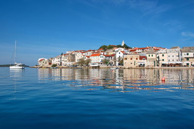 Buildings by sea against blue sky