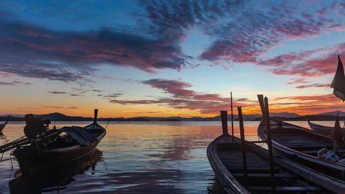 Boat moored in sea against sky during sunset