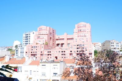 Buildings in city against clear blue sky