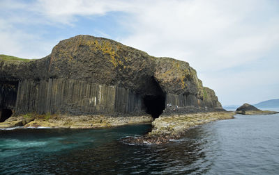 Rock formation in sea against sky