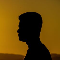 Side view of silhouette man against clear sky during sunset