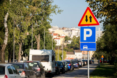 Road sign by trees in city