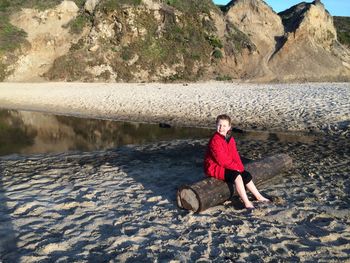 Boy sitting on tree trunk at beach