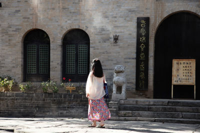 Rear view of woman standing at entrance of building