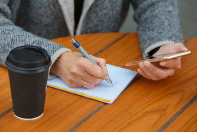 Close-up of man holding paper with bag on table