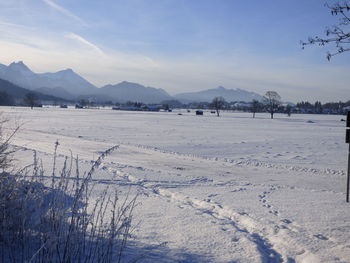 Scenic view of snow covered field by mountains against sky