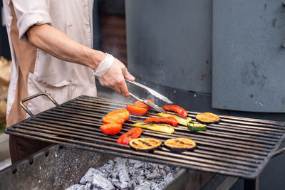 Vegetables are on the grill . the coals are smoking