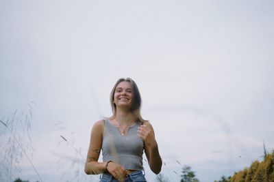 Portrait of young woman standing against sky