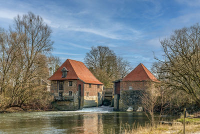 House by lake against sky during winter