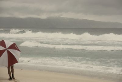 Woman standing at beach against sky