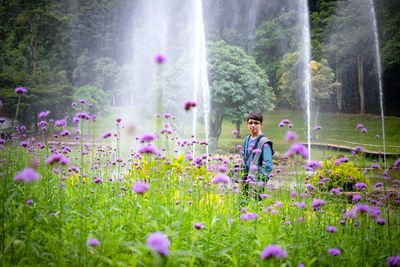 Portrait of man standing amidst flowering plants on land