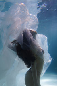 Woman with curtain swimming in pool