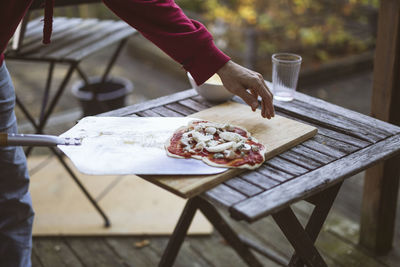 Man putting homemade pizza on pizza peel