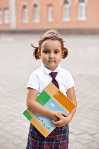 Portrait of smiling girl holding book outdoors