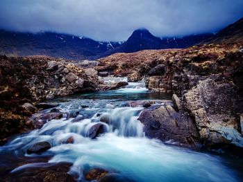 River flowing amidst rocks against sky