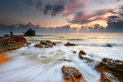 Scenic view of seascape by rock during sunset