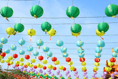 Low angle view of multi colored balloons hanging against sky