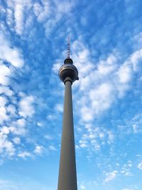 Low angle view of communications tower against cloudy sky