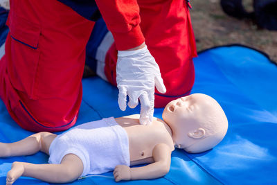 Midsection of person practicing cpr on dummy outdoors
