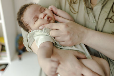 Mother touching cheeks and pampering baby girl at home