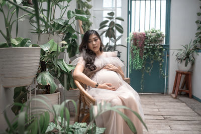 Young woman sitting by potted plants