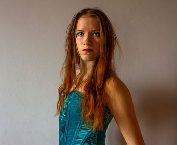 Portrait of young woman standing against wall