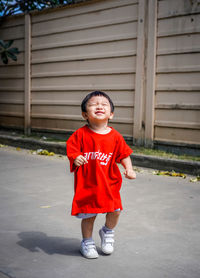 Portrait of cute girl standing against wall