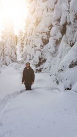 Rear view of person on snow covered rock during winter