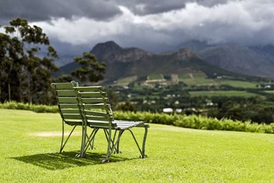 Empty chairs on field against sky