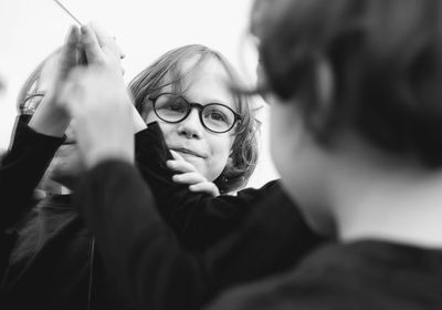 Close-up of siblings playing with mirror against sky