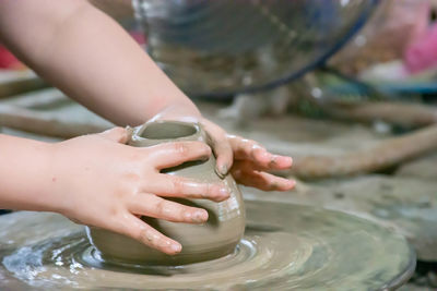 The fingers are shaped clay pot on a rotating tray.