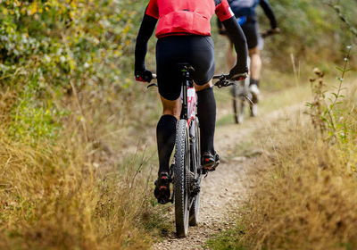 Low section of man riding bicycle on field