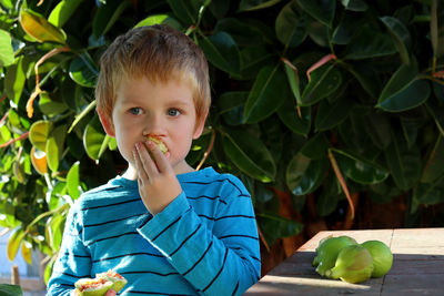 Portrait of young man standing against plants