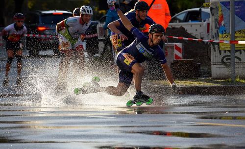 People skating on wet street in city