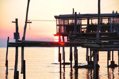 Pier on sea against sky during sunset