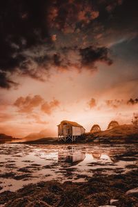 Abandoned building by sea against sky during sunset